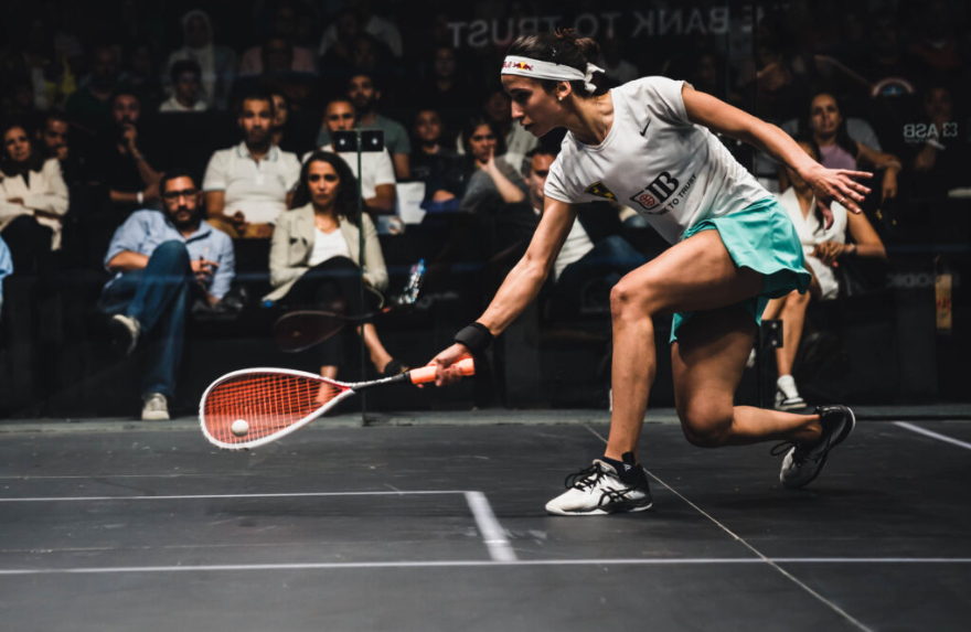 A girl is playing squash in front of an audience